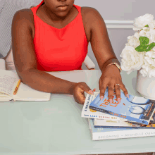 a woman sits at a desk holding a book titled becoming