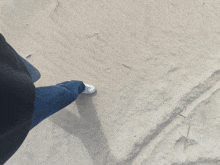 a person is walking on a sandy surface with a black shirt on