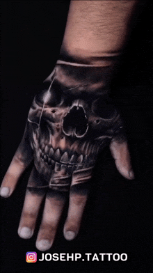 a close up of a hand with a skull tattoo on it