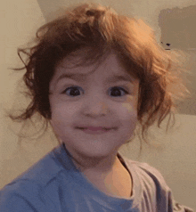 a little girl with curly hair is making a funny face .