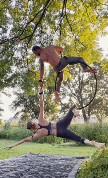 a man and a woman are performing aerial acrobatics in a park