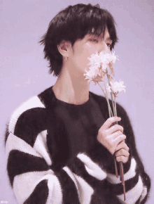 a man in a black and white striped sweater is holding flowers in his hands