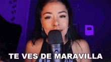 a woman is singing into a microphone and the words te ves de maravilla are above her