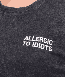 a close up of a person wearing a t-shirt that says allergic to idiots on it