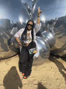 a woman giving a peace sign while standing in front of a mirror ball