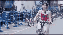 a woman is riding a bike in a parking lot with bikes parked in front of a fence with the number 10 on it