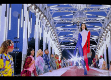 a woman in a red white and blue jumpsuit walks down a runway