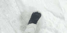 a person 's foot is standing in the snow wearing black boots .