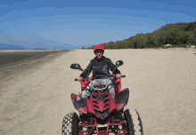 a man riding a red atv on the beach