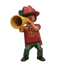 a toy figure is wearing a red and green hat and blowing a yellow horn