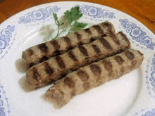 three grilled sausages on a white plate with parsley .