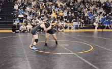 two women are wrestling on a wrestling mat in front of a crowd of people .