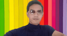 a man wearing sunglasses is standing in front of a rainbow background