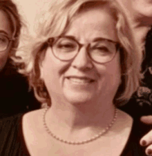 a woman wearing glasses and a necklace is smiling