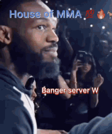 a man with a beard stands in front of a crowd and says house of mma 100 banger server w