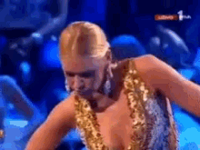 a woman in a gold and silver dress is dancing on stage