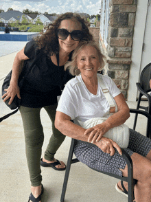 a woman standing next to an older woman in a chair