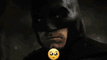 a close up of a man wearing a batman mask with a sad face on it .