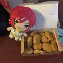 a stuffed animal with red hair sits next to a box of nuggets