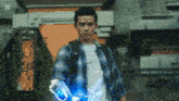 a young man in a plaid shirt is holding a glowing object in his hand .