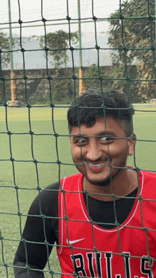 a man in a bulls jersey looks through a net