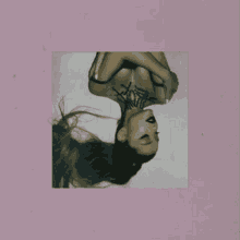 ariana grande is hanging upside down on a pink background .