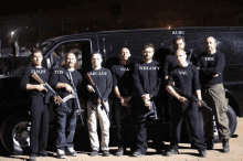 a group of men standing in front of a van wearing black shirts with their names on them