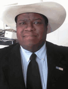 a man wearing a white cowboy hat and a black tie