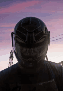 a person wearing a black helmet with a purple sky behind them