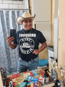 a man wearing a cowboy hat and a t-shirt that says troquero takes a selfie