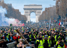 a crowd of people in yellow vests are gathered in front of a large archway