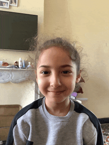 a young girl is smiling in front of a fireplace