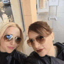 two women wearing sunglasses and jackets are posing for a picture .