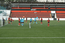 a group of soccer players on a field with the word sport on the side of the stadium