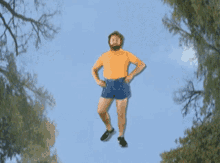 a man in a yellow shirt and blue shorts is jumping into the air