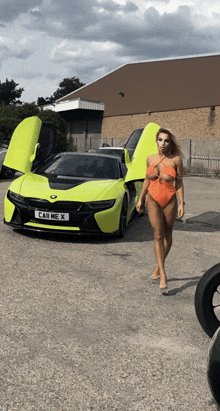 a woman in a bathing suit is standing in front of a car that has a license plate that says car me x