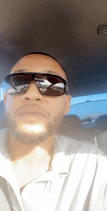 a man wearing sunglasses and a white shirt is in a car