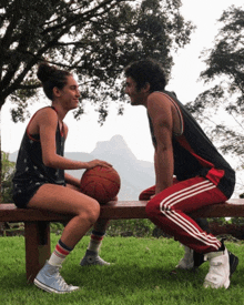 a man and a woman are sitting on a bench holding a basketball