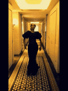 a woman in a black dress is standing in a hallway