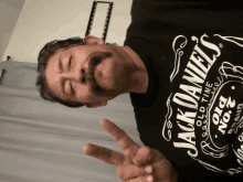 a man wearing a jack daniel 's t-shirt giving a peace sign