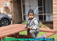 a little boy in a suit sits on a picnic table with the words thank you so much for warm birthday wishes above him