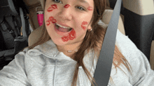 a woman sitting in a car with red lipstick kisses on her face