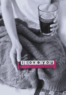 a person is holding a glass of soda and a pink block that says i love you