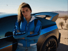 a woman in a blue jacket stands next to a car