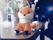 a stuffed fox sits on a table in front of a potted plant