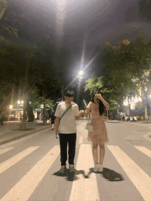 a man and a woman crossing the street at night