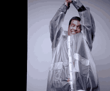 a man wearing a clear plastic raincoat with his arms in the air