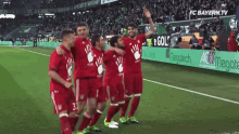 a group of soccer players are posing for a picture on a field with an ad for fc bayern.tv in the background