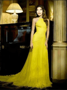 a woman in a yellow dress stands next to a lamp