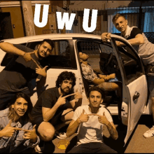 a group of young men are posing in front of a white car with the word uwu written on it